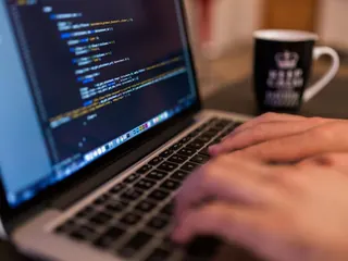 Manos escribiendo código en una laptop